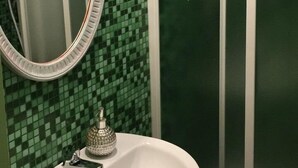 Une salle de bain avec un lavabo blanc, un miroir et une cabine de douche.