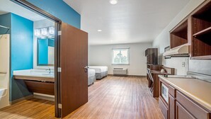 A modern bathroom with a wooden vanity, a large mirror, and a shower area. - WoodSpring Suites Naples East (Naples)