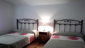 Un dormitorio con dos camas individuales, cada una con una colcha estampada y una mesita de noche con una lámpara entre ellas.