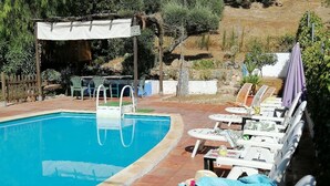 Una piscina con tumbonas y una pérgola.