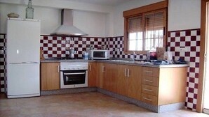 Una cocina con refrigerador, estufa, microondas y armarios de madera.