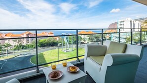 Un balcó amb vista a la ciutat, una taula amb croissants i suc, i un sofà blanc.