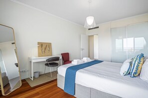 Una habitación de hotel con cama, escritorio, silla, espejo y ventana.