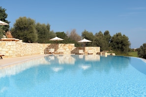 Piscine extérieure en saison, piscine à débordement, chaises longues