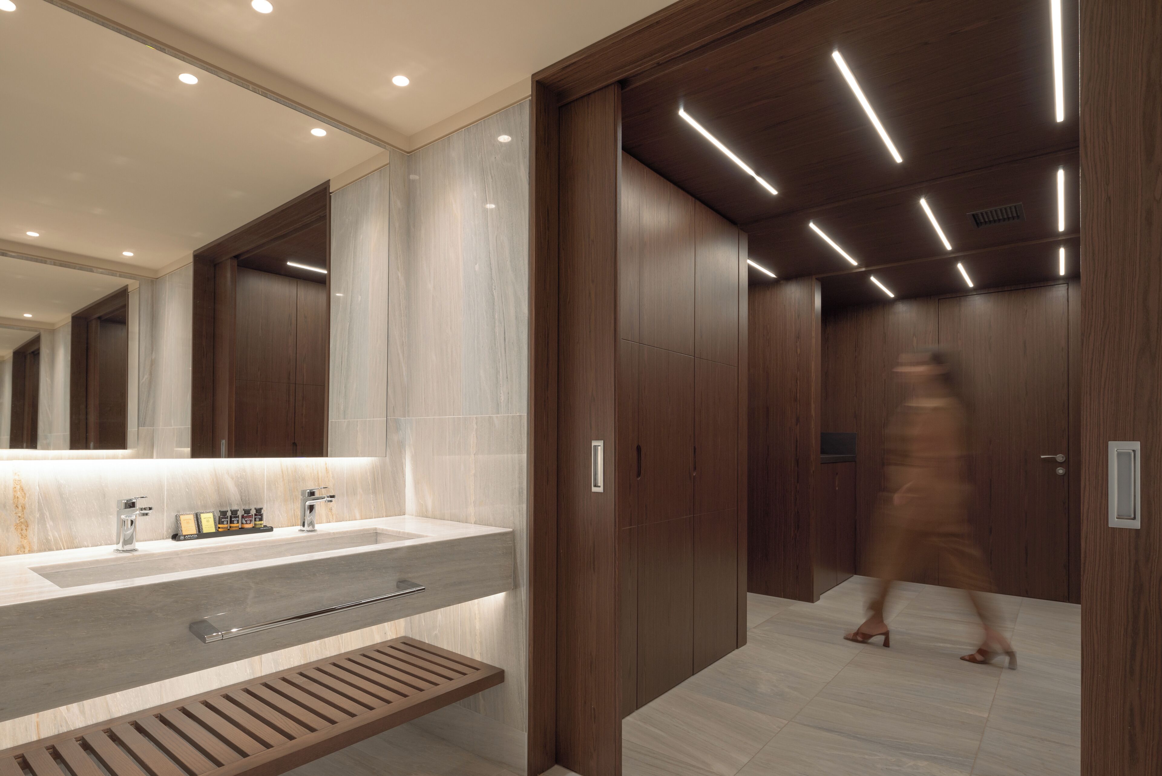 A modern bathroom with a large mirror, a sink, and a wooden vanity.
