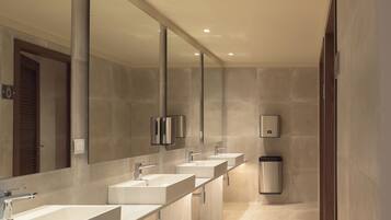 A modern bathroom with three sinks, a large mirror, and a hand dryer.