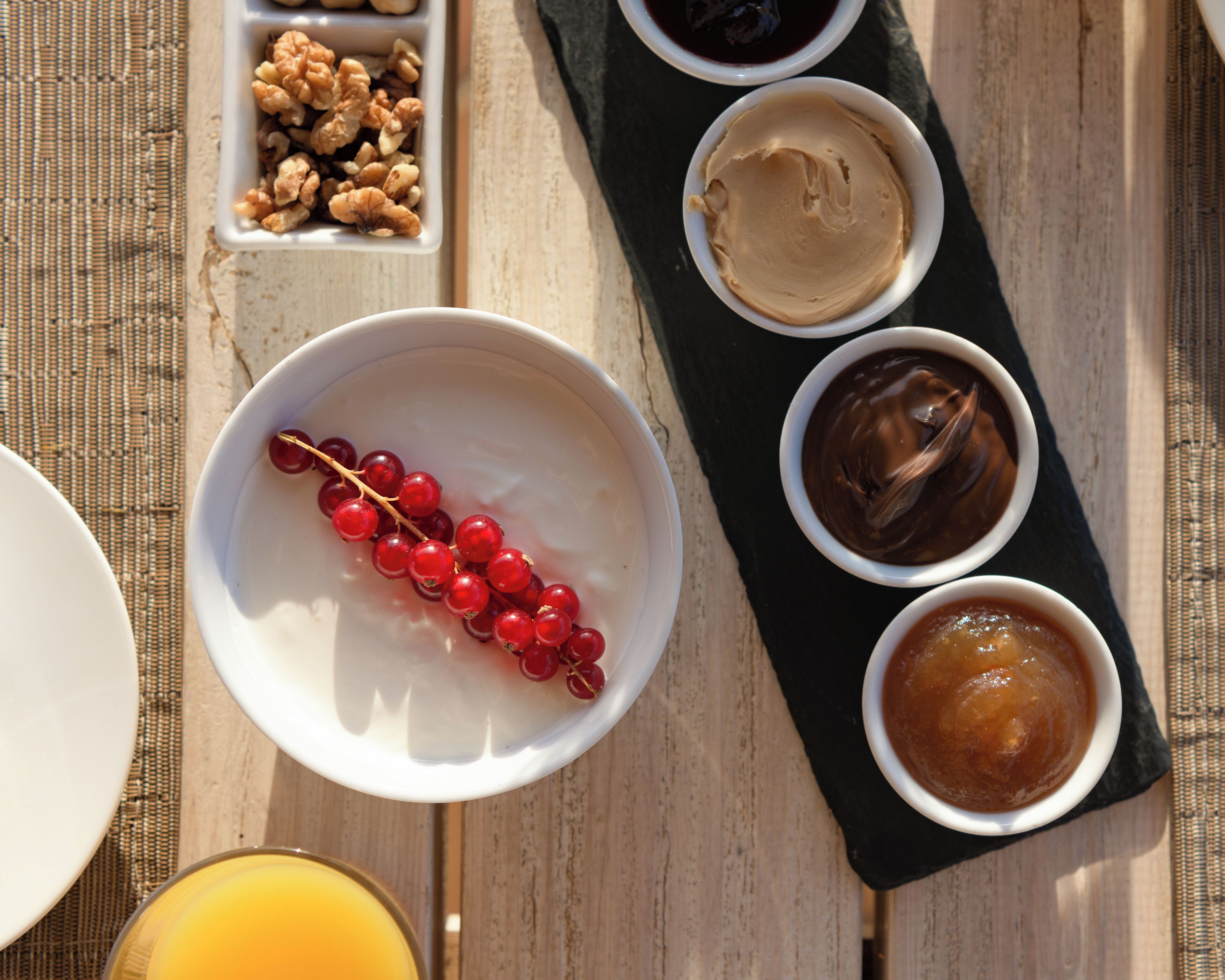 Desayuno servido con tazones de comida y un vaso de jugo de naranja sobre una mesa de madera.