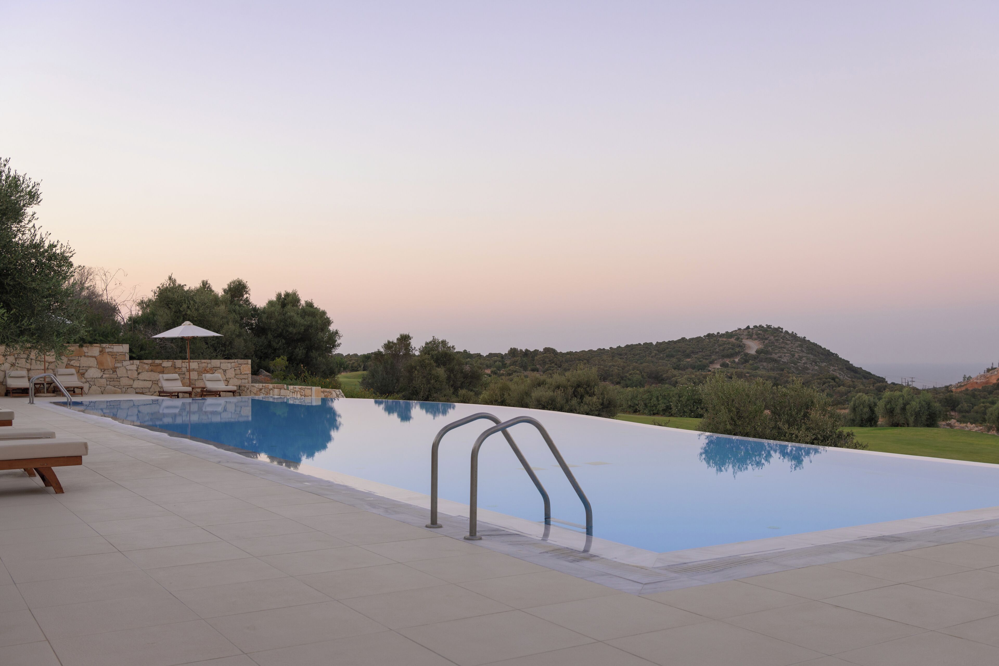 Una piscina con muretto in pietra e lettini.