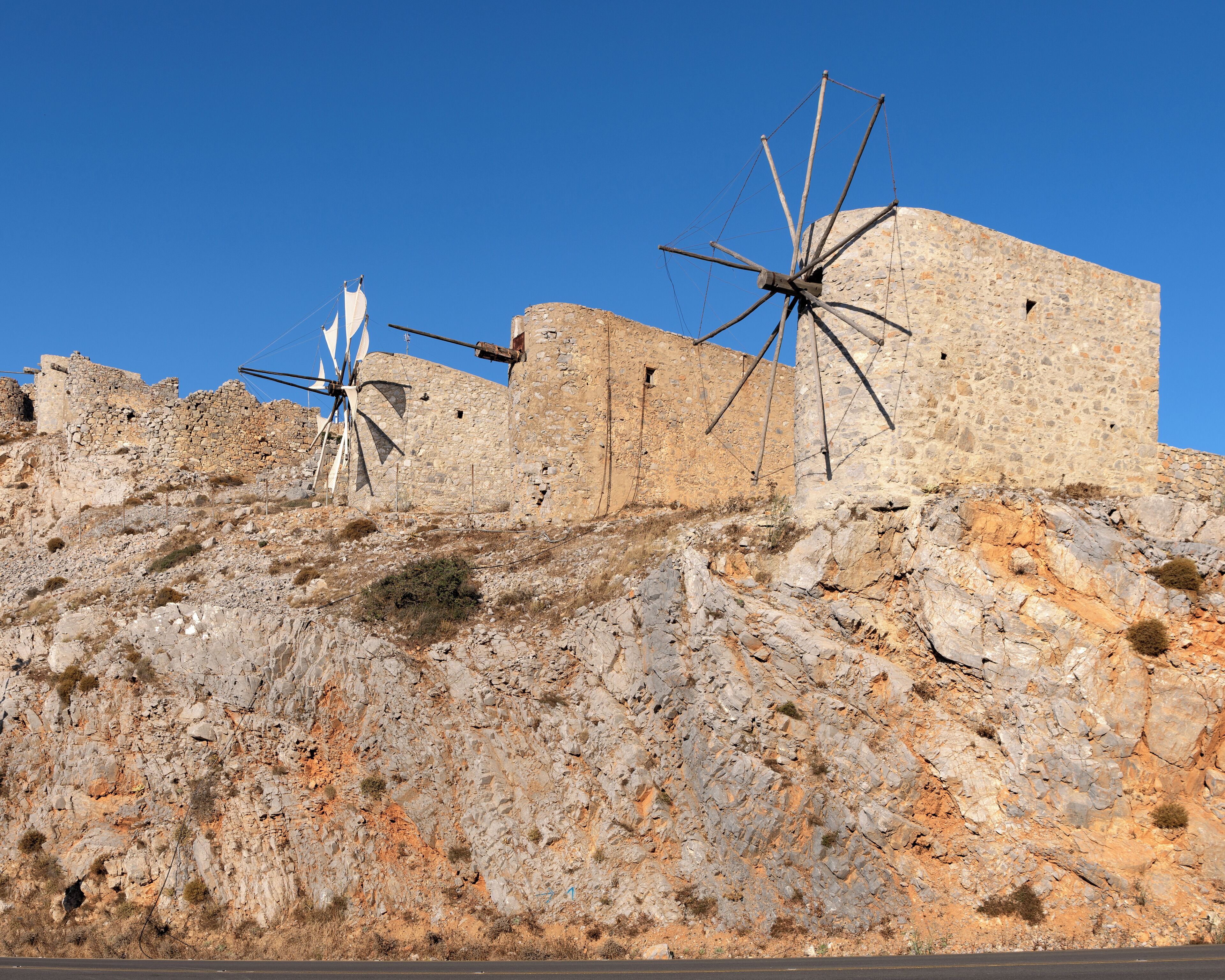 A stone building with a windmill on a hill.