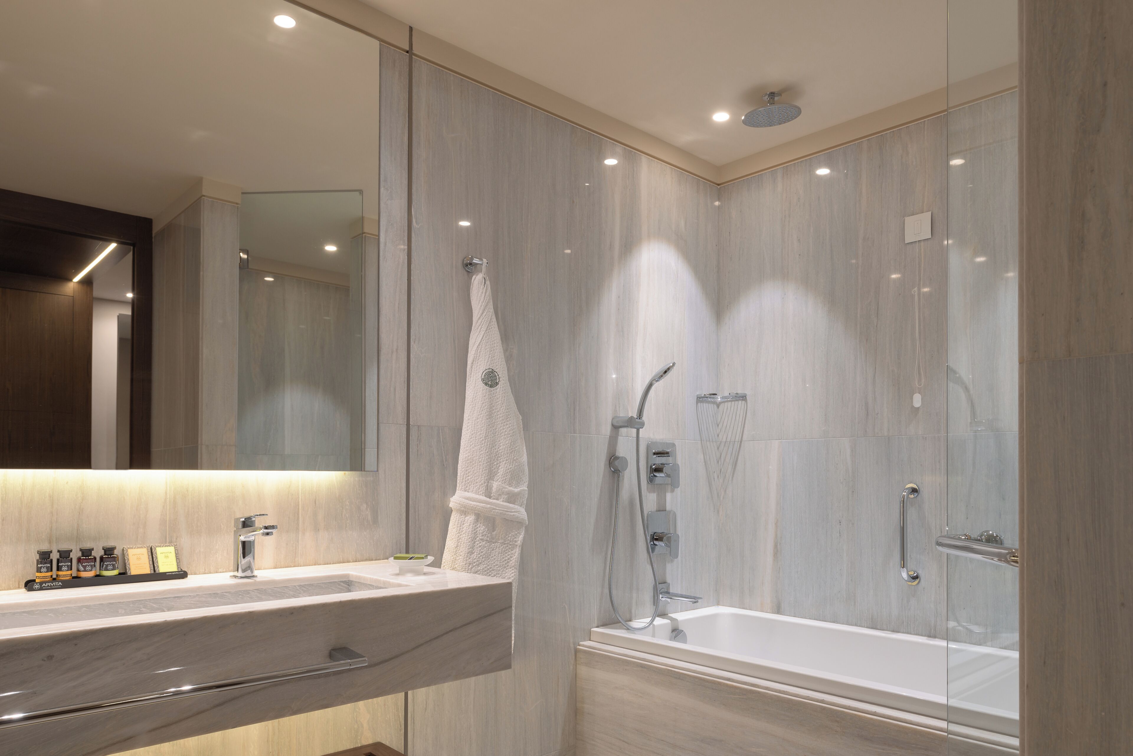 A modern bathroom with a large mirror, a bathtub, and a vanity with a sink.