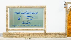 Kehyksiin asetettu kyltti, jossa lukee yläosassa teksti ”riad mediterraneo Barbate ” ja sen alla espanjankielinen lause.