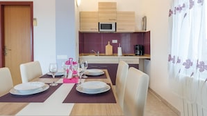 Un coin repas avec une table dressée pour quatre personnes, un four à micro-ondes et une machine à café dans la cuisine.