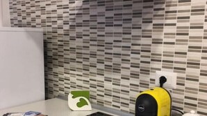 Une cuisine au design moderne, dotée d’une plaque de cuisson à induction noire, d’une machine à café jaune et noire, et d’un logo vert et blanc sur le plan de travail.