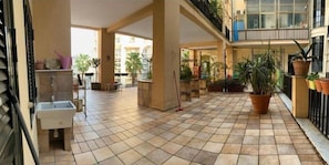 A spacious outdoor area with tiled flooring, potted plants, and a sink.
