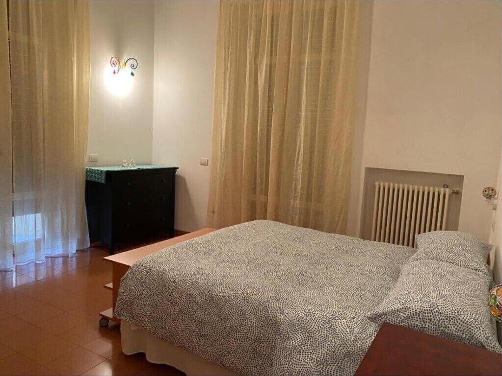A bedroom with a bed, a dresser, and a radiator.