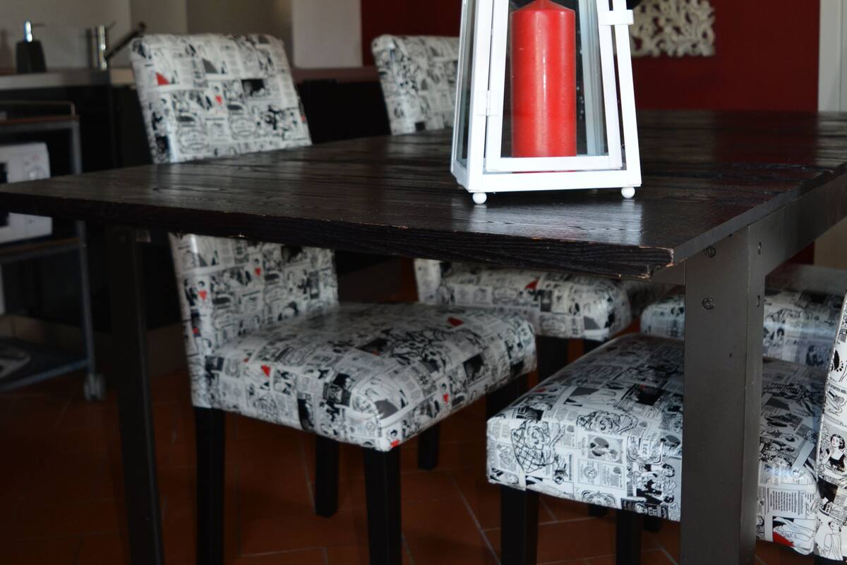 A dining area with a dark wooden table, patterned chairs, and a white lantern with a red candle.