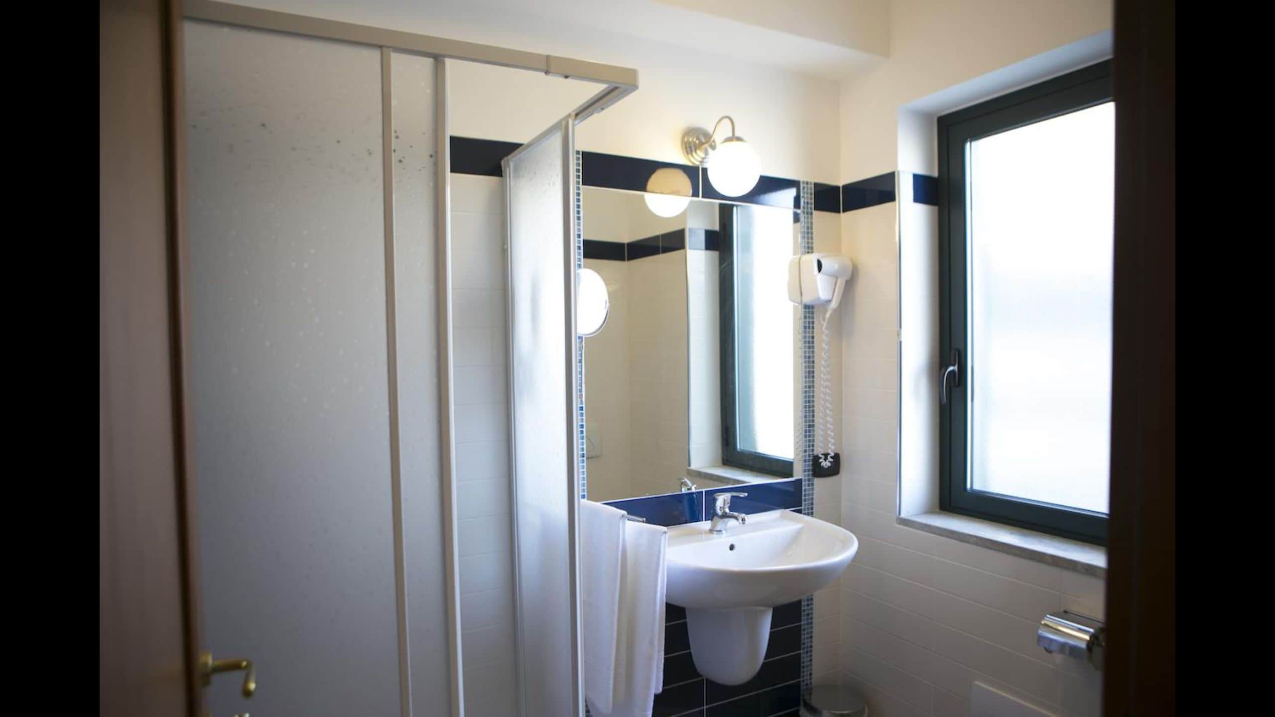 A bathroom with a white sink, a mirror, and a window.