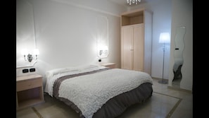 A bedroom with a bed, bedside tables, a wardrobe, and a floor lamp.