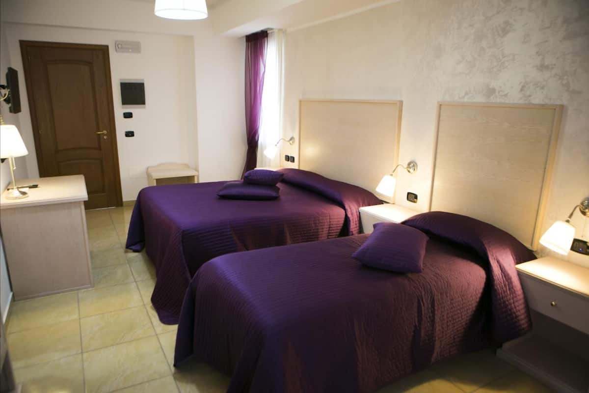 Een hotelkamer met twee bedden, een bureau, een stoel en een klein tafeltje.