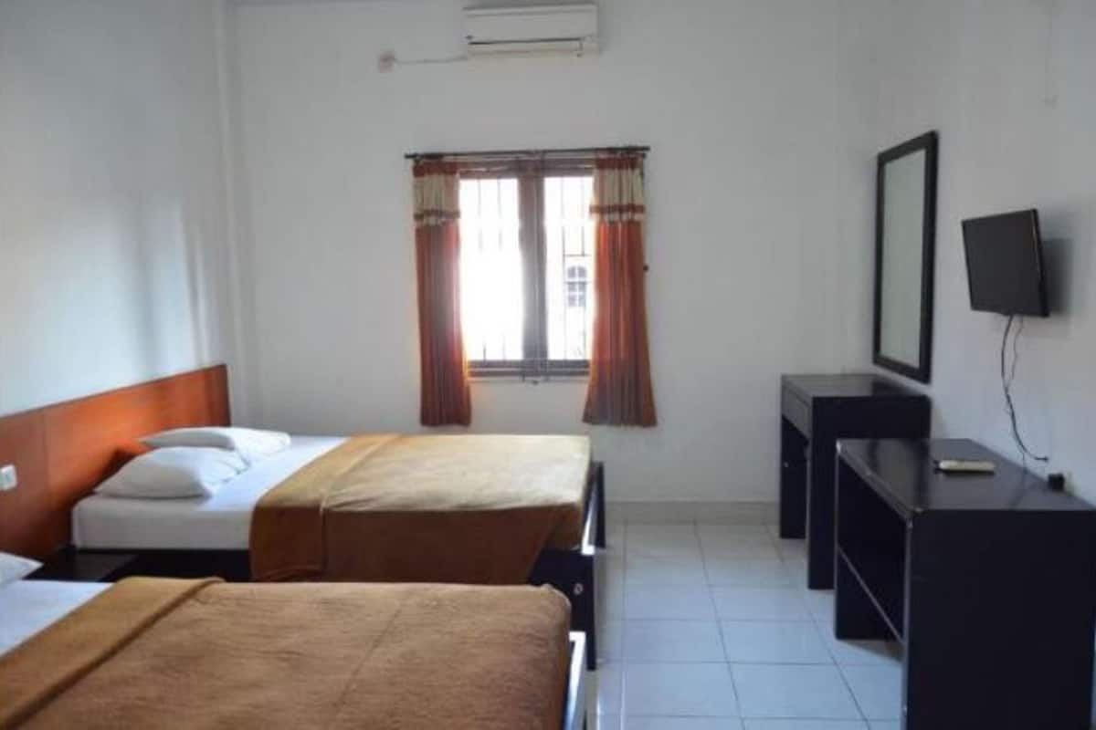 A hotel room with two beds, a desk, a chair, a TV, and a window with curtains.