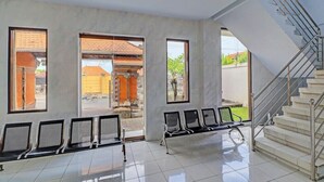 A spacious waiting area with a staircase and a view of a traditional building outside. - Hotel Nuansa Indah (Denpasar)