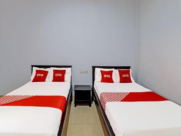 A hotel room with two single beds, each with a red and white bedspread and pillows featuring the "OYO" logo. - Hotel Nuansa Indah (Denpasar)
