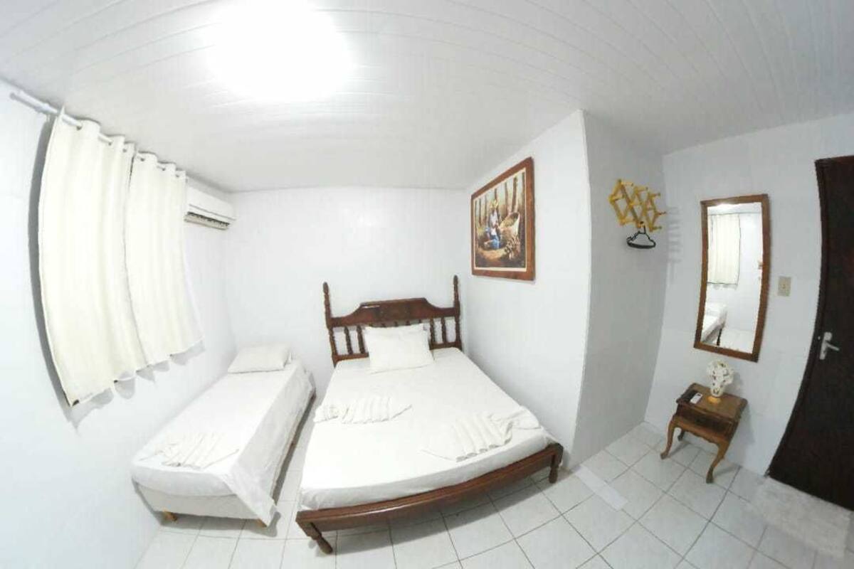 A bedroom with a single bed, a bedside table, a mirror, and a door.