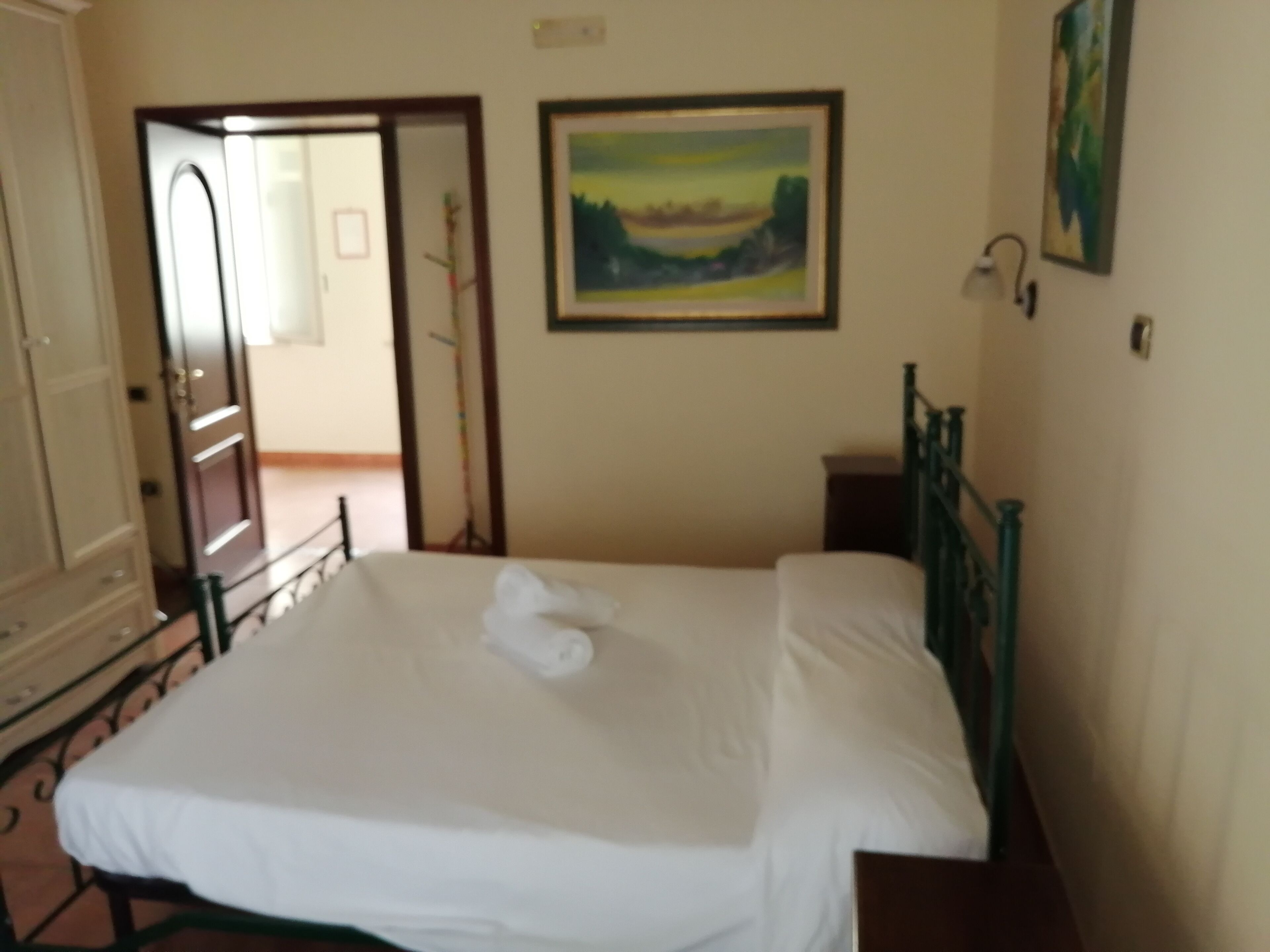 Un dormitorio con cama, puerta, un cuadro y ventana.