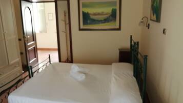Un dormitorio con cama, puerta, un cuadro y ventana.