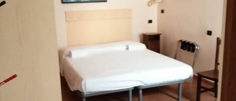 A bedroom with a bed, a chair, a wall-mounted air conditioner, and a painting.