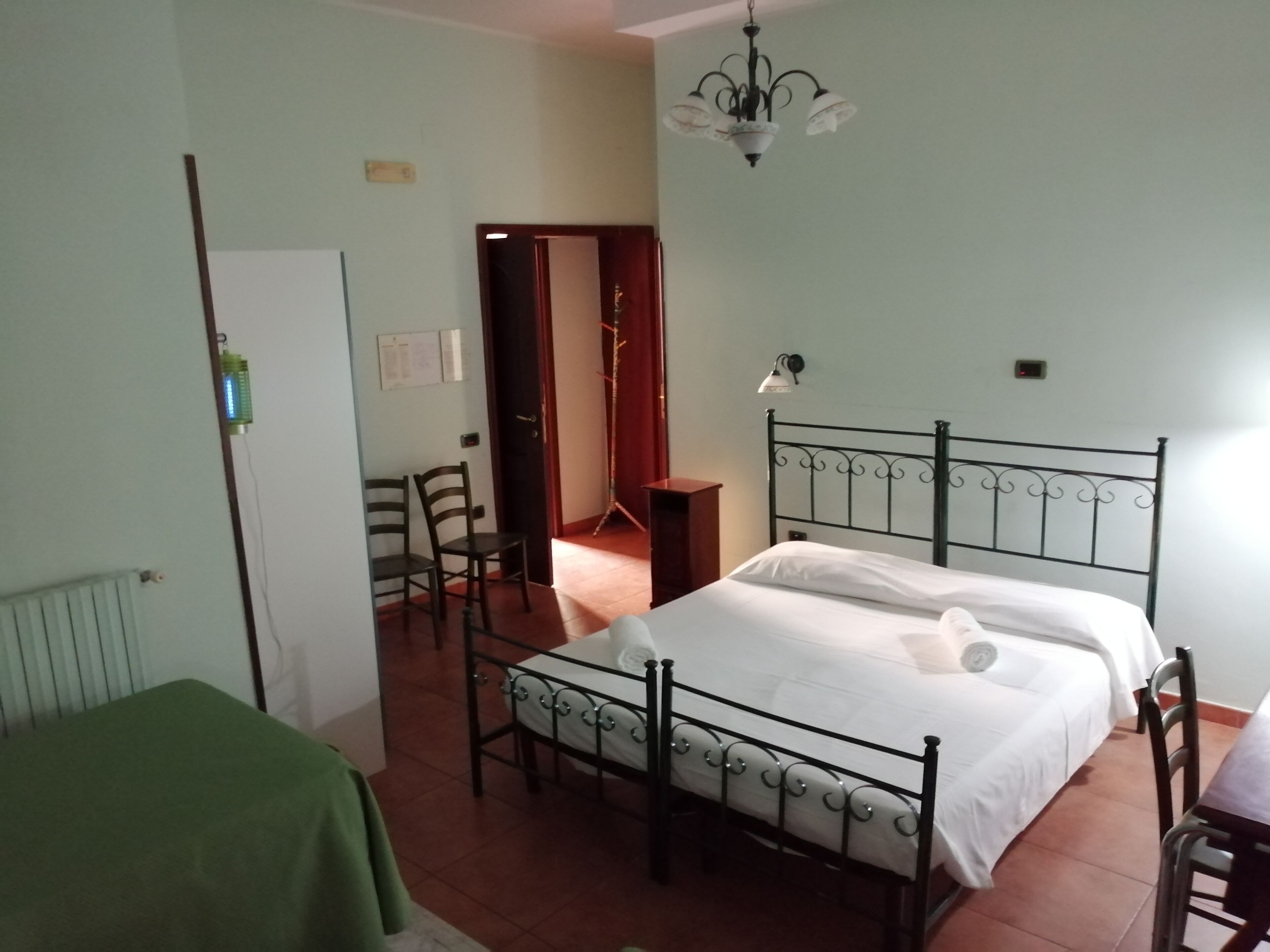 Quarto com cama, cadeira, mesa e radiador.
