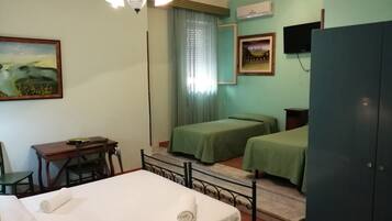 Habitación de hotel con dos camas, un escritorio, una silla, un armario y una lámpara en el techo.