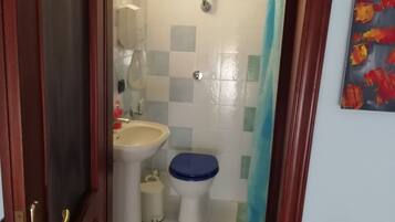 Ein kleines Badezimmer mit Toilette, Waschbecken und Duschvorhang.