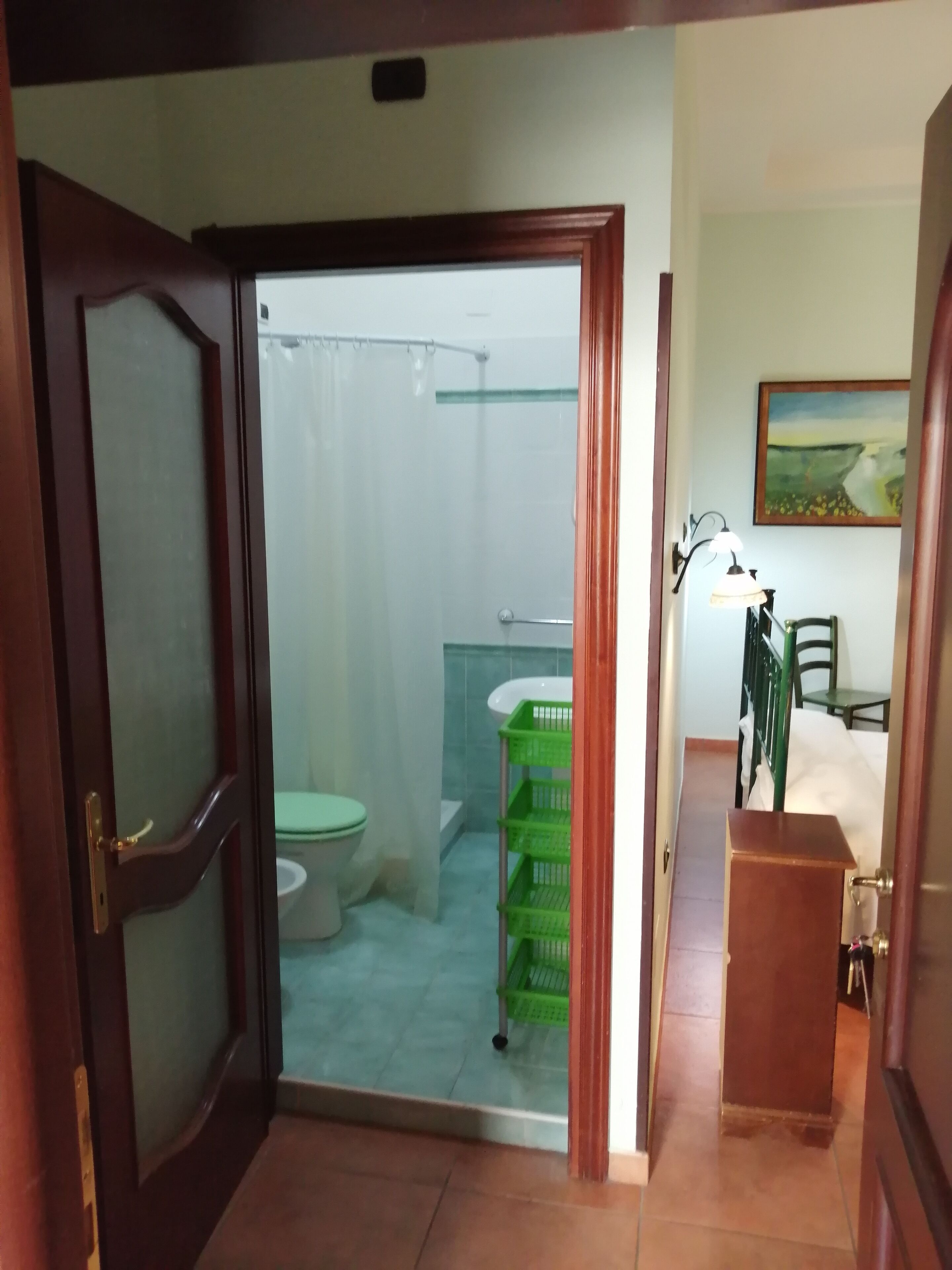 Un baño con inodoro, ducha y cestas de plástico verde.