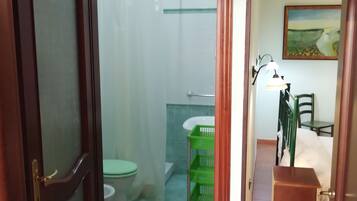 Un baño con inodoro, ducha y cestas de plástico verde.