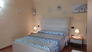 Une chambre à coucher avec un lit, deux tables de chevet avec des lampes, une horloge murale et un tableau décoratif.