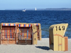 Beach chairs with numbers, a sandy beach, and the ocean with boats in the distance.