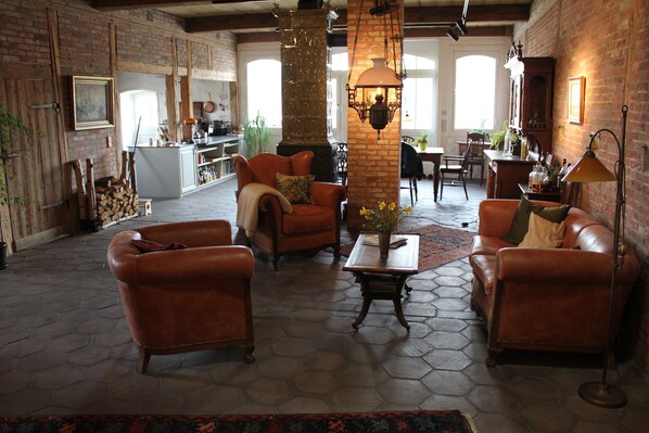 A spacious living room with leather sofas, a coffee table, and a brick fireplace.