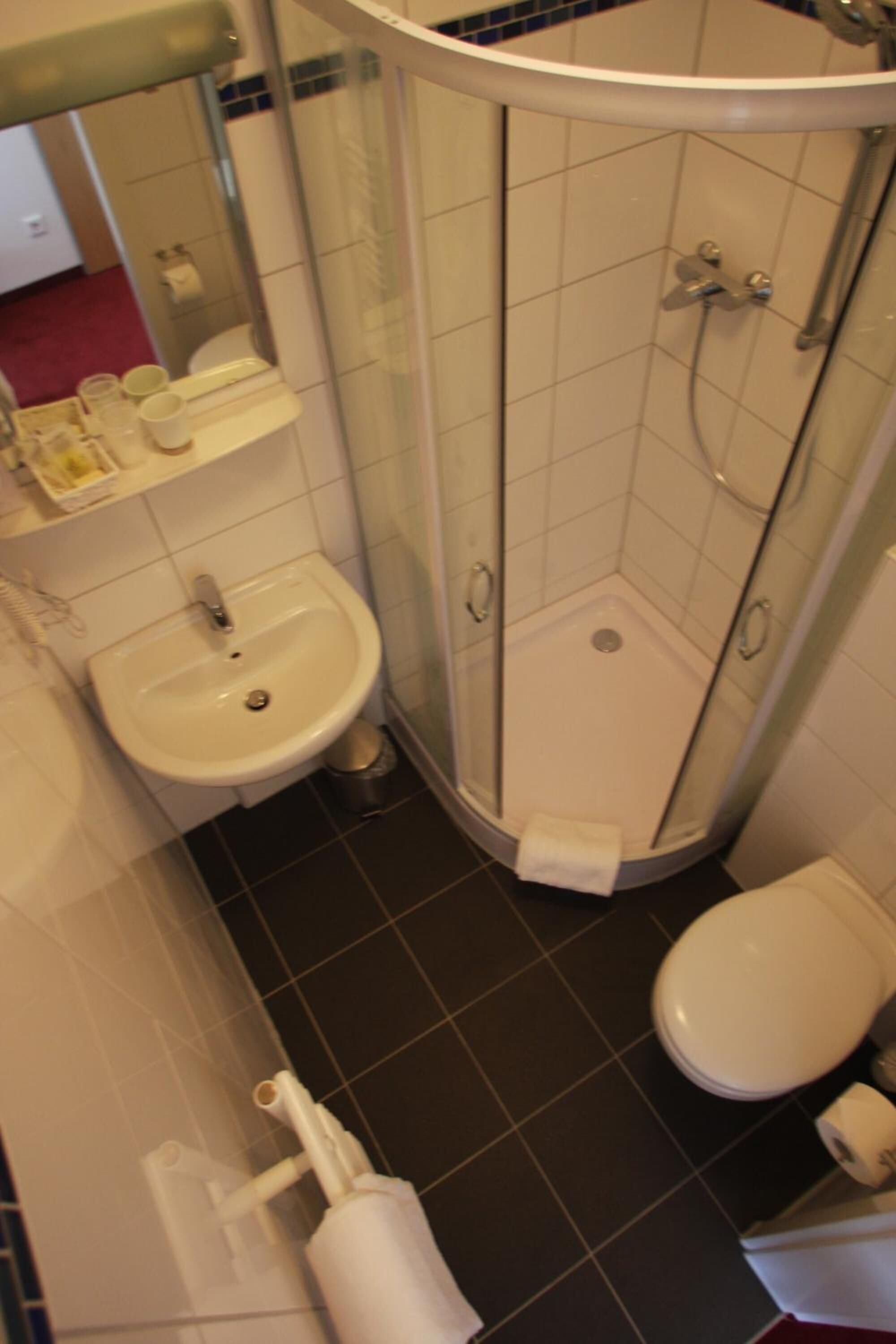 Un baño con lavamanos, inodoro y ducha con mampara de vidrio.