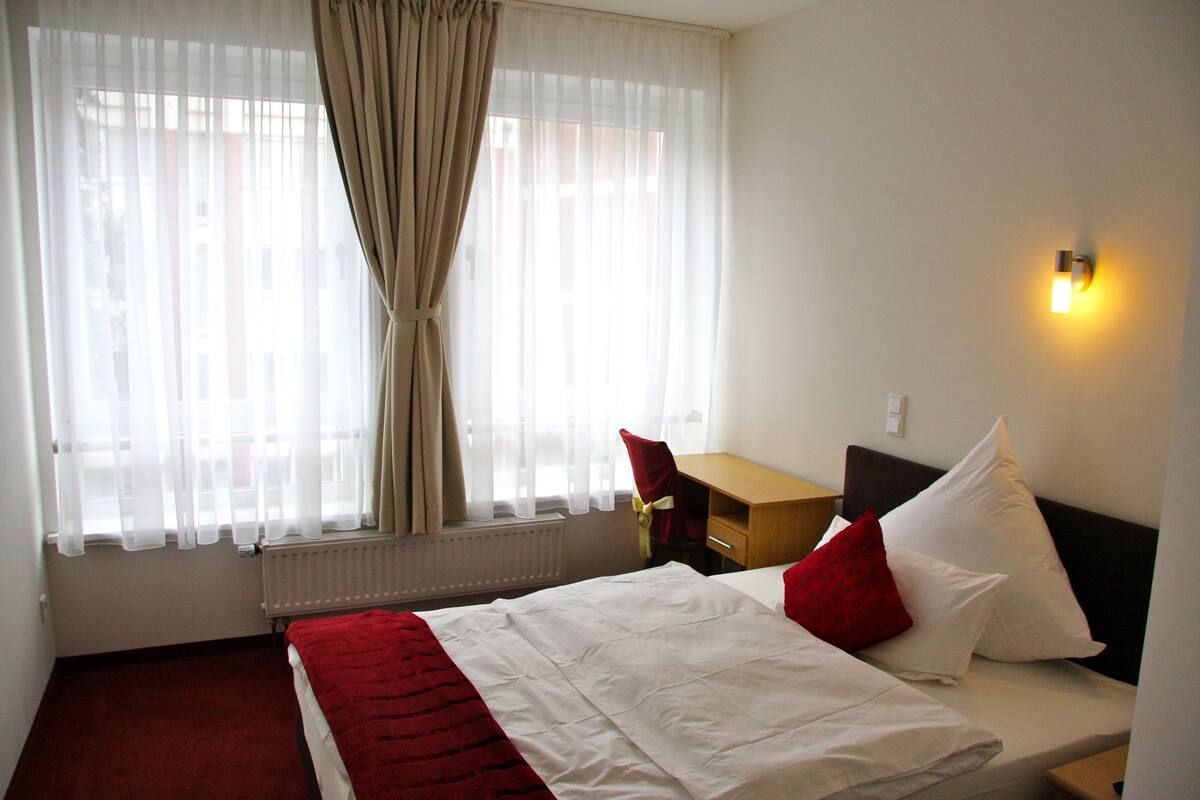 Ein Hotelzimmer mit Bett, Schreibtisch und Stuhl.