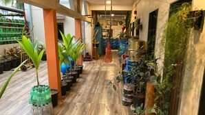 A hallway with wooden flooring, potted plants, and a blue cabinet in the background. - Dream Vision Guest House (Diu)