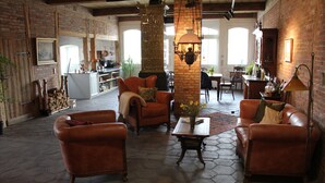 A spacious living room with leather sofas, a coffee table, and a brick fireplace. - App. Morniglight, flooded by the sun (Luhnstedt)