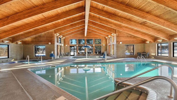 Una piscina interior con vigas de madera, agua cristalina y un indicador de profundidad de 30 pies.