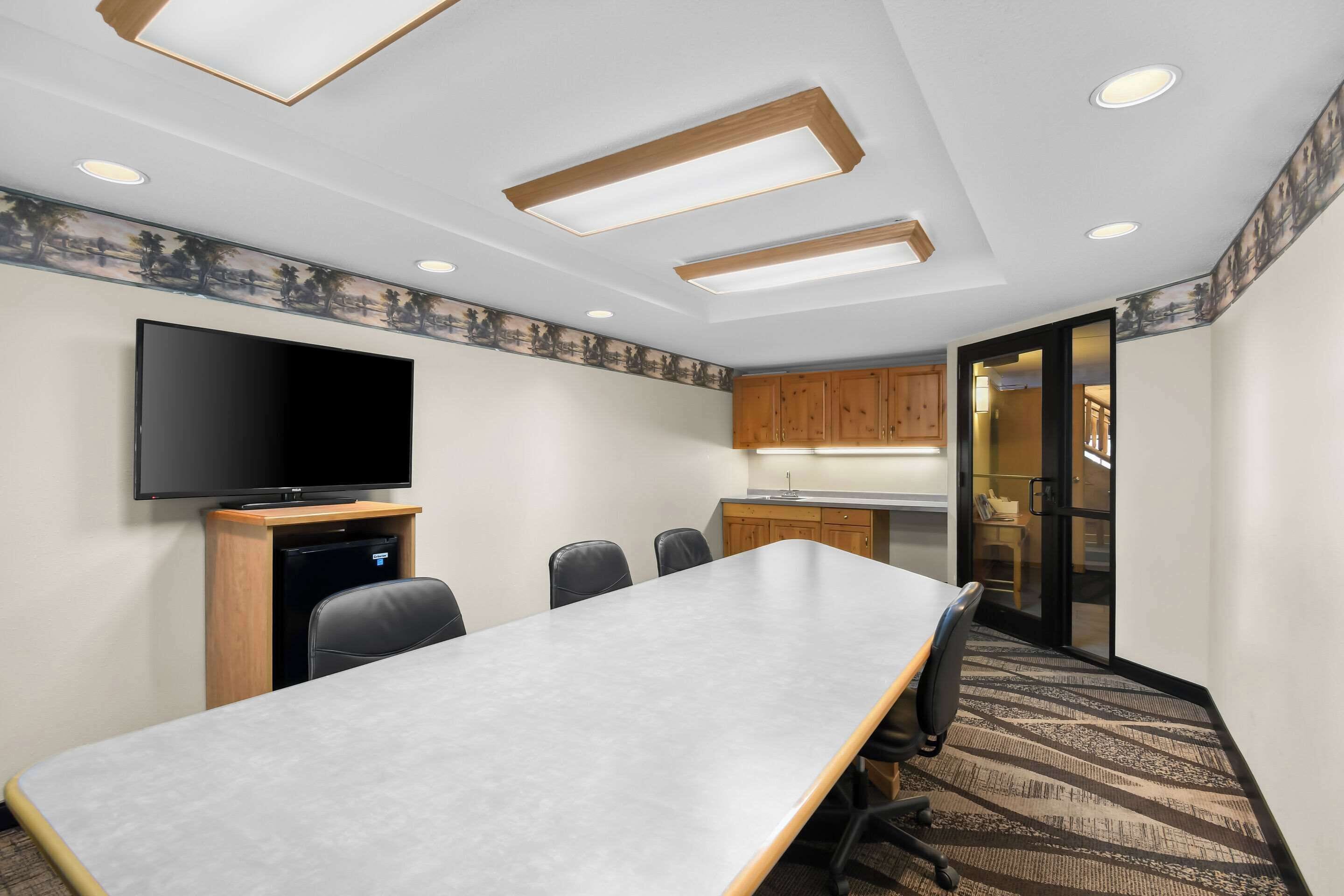 A conference room with a long table, chairs, a flat-screen TV, and built-in cabinets.