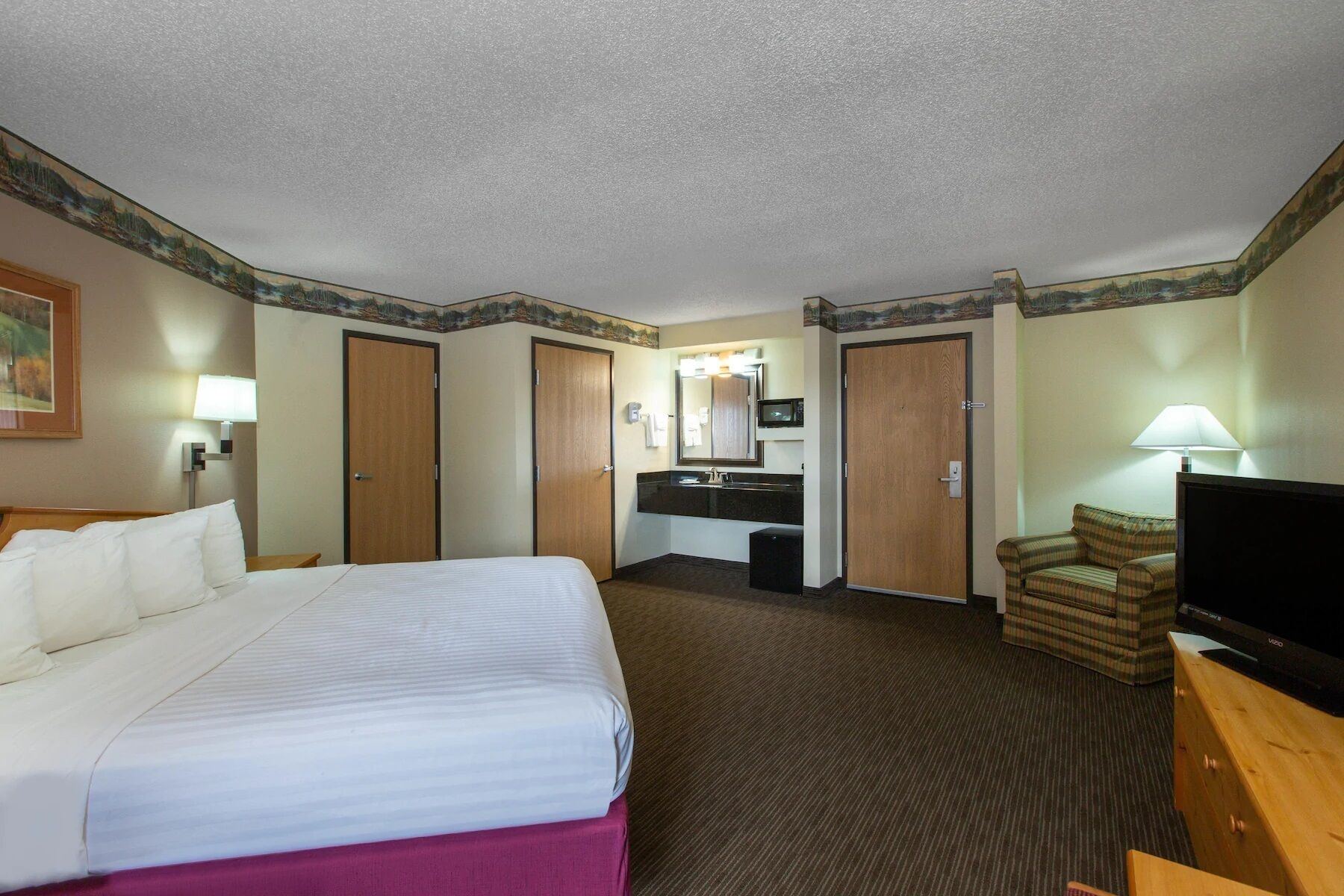 A hotel room with a bed, a desk with a computer, a television, and a couch.
