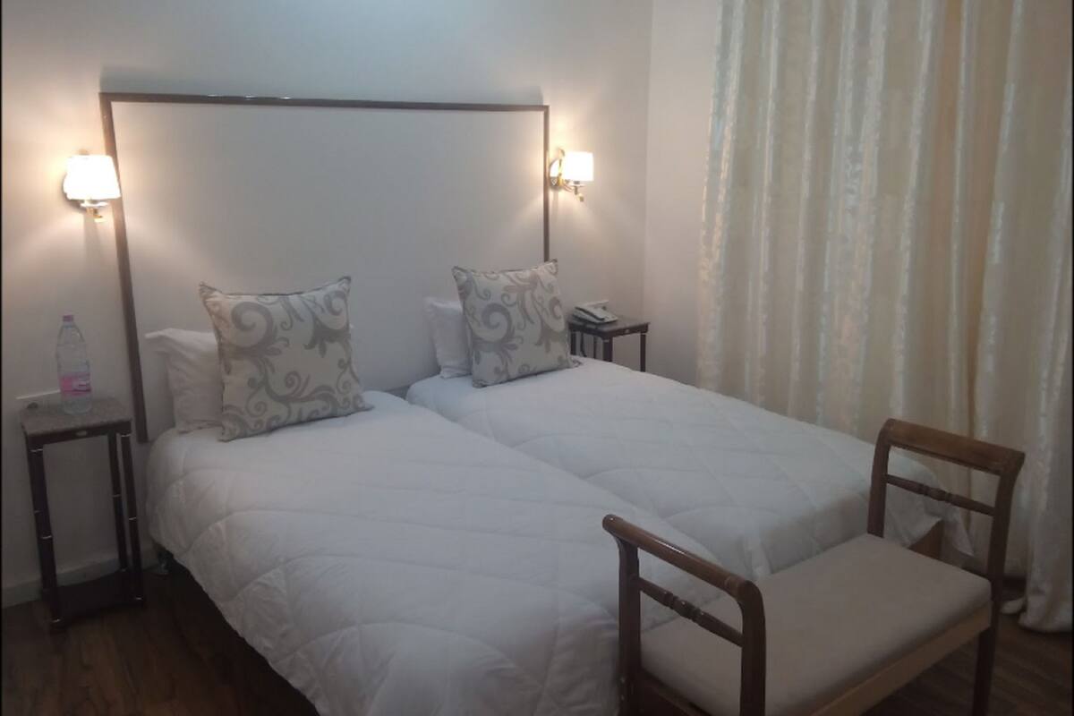 A double bed with two pillows, a bedside table with a lamp, and a chair.