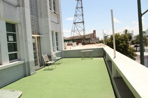A rooftop terrace with artificial grass, two white chairs, and a table. - Hotel Plaza del Arco Express (Monterrey)