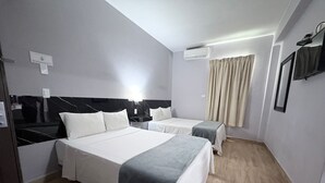 A hotel room with two beds, a flat-screen TV, an air conditioning unit, and a window with curtains. - Hotel Plaza del Arco Express (Monterrey)
