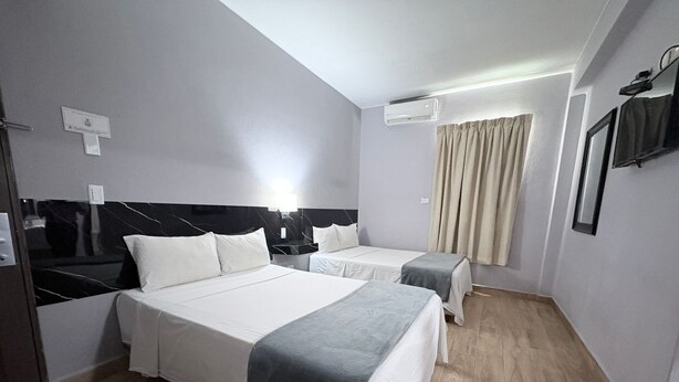 A hotel room with two beds, a flat-screen TV, an air conditioning unit, and a window with curtains. - Hotel Plaza del Arco Express (Monterrey)