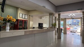 A reception desk with a vase of sunflowers, a television, and framed certificates on the wall. - Hotel Plaza del Arco Express (Monterrey)